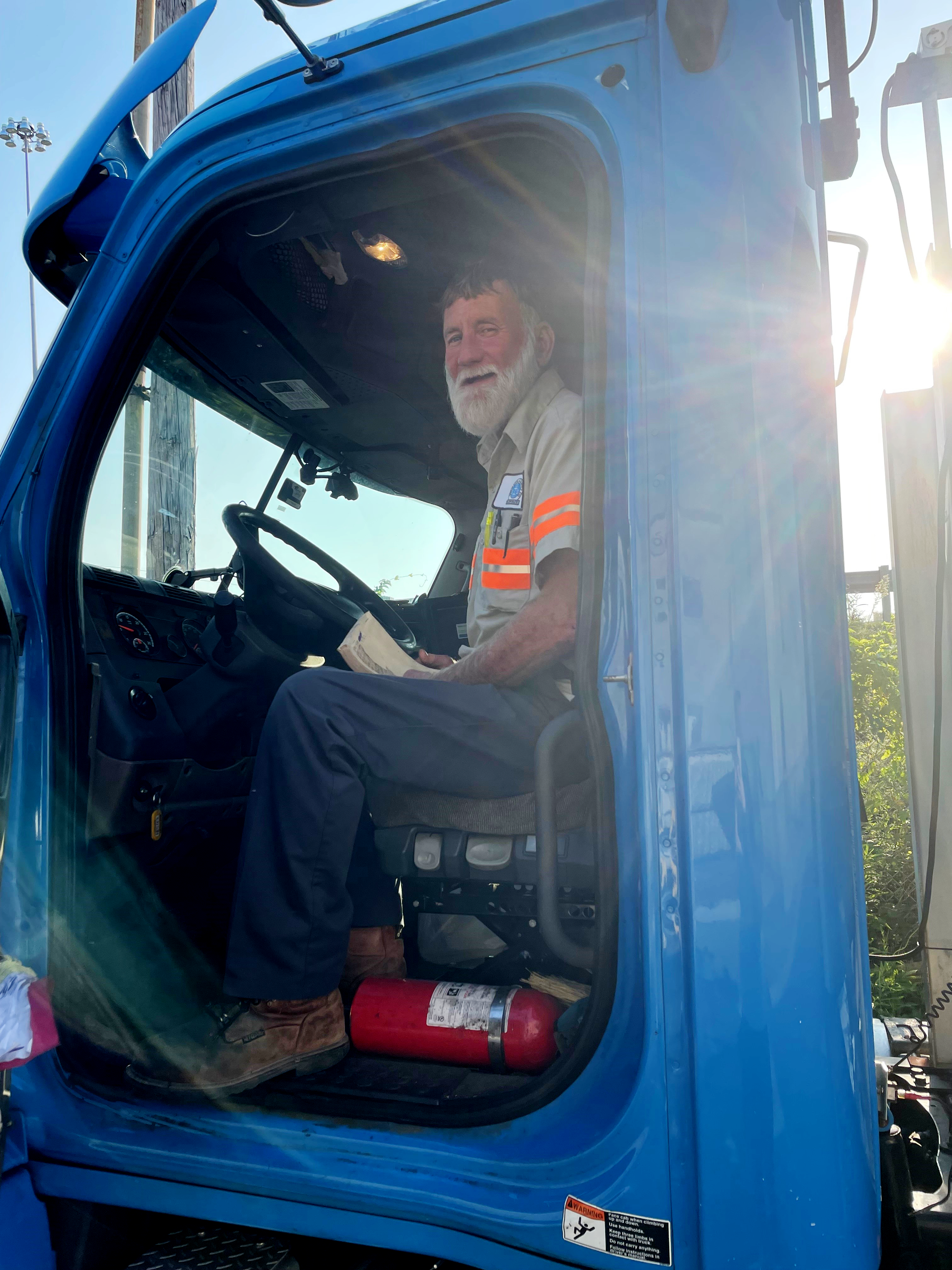Siskin truck driver sitting in his cab with the sun shining.