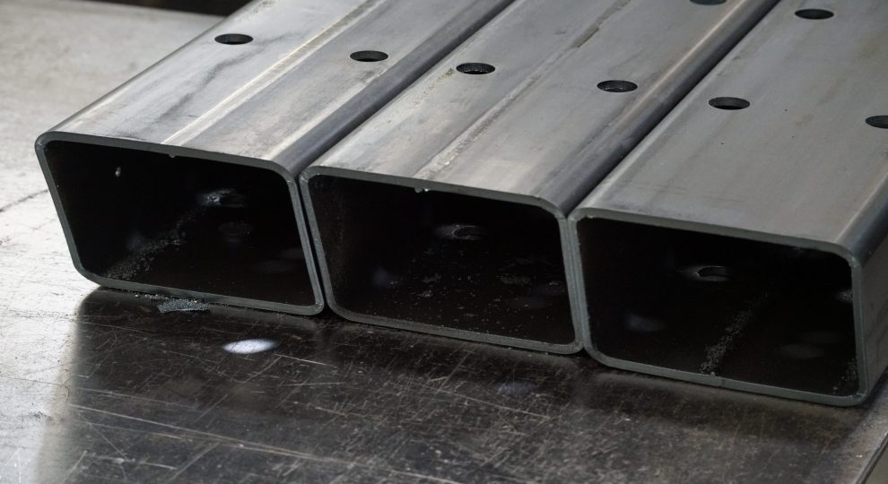 three rounded rectangular tubes laying on a desk with holes in the material