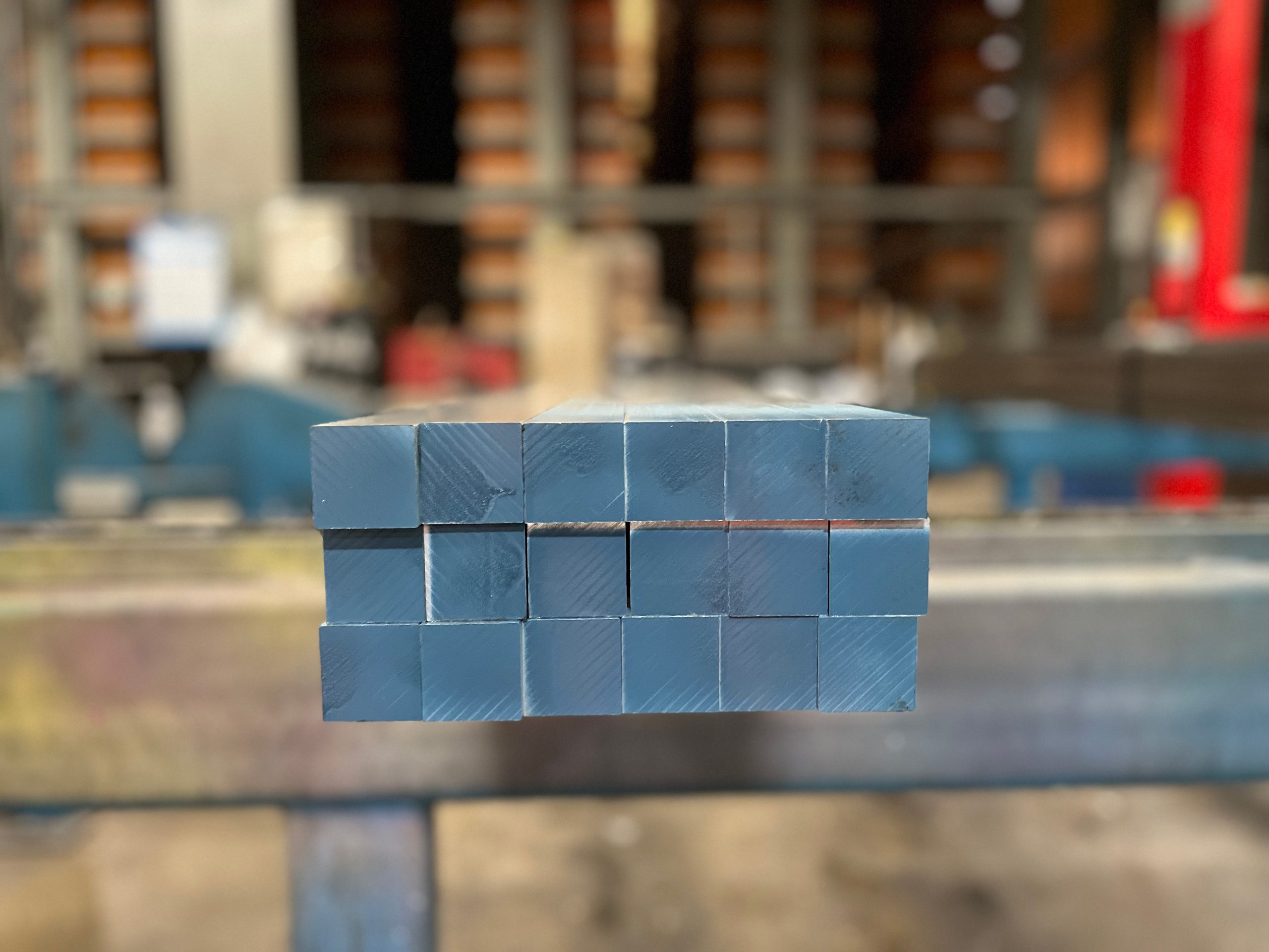 Bundle of aluminum square bar stacked on top of each other in an industrial setting