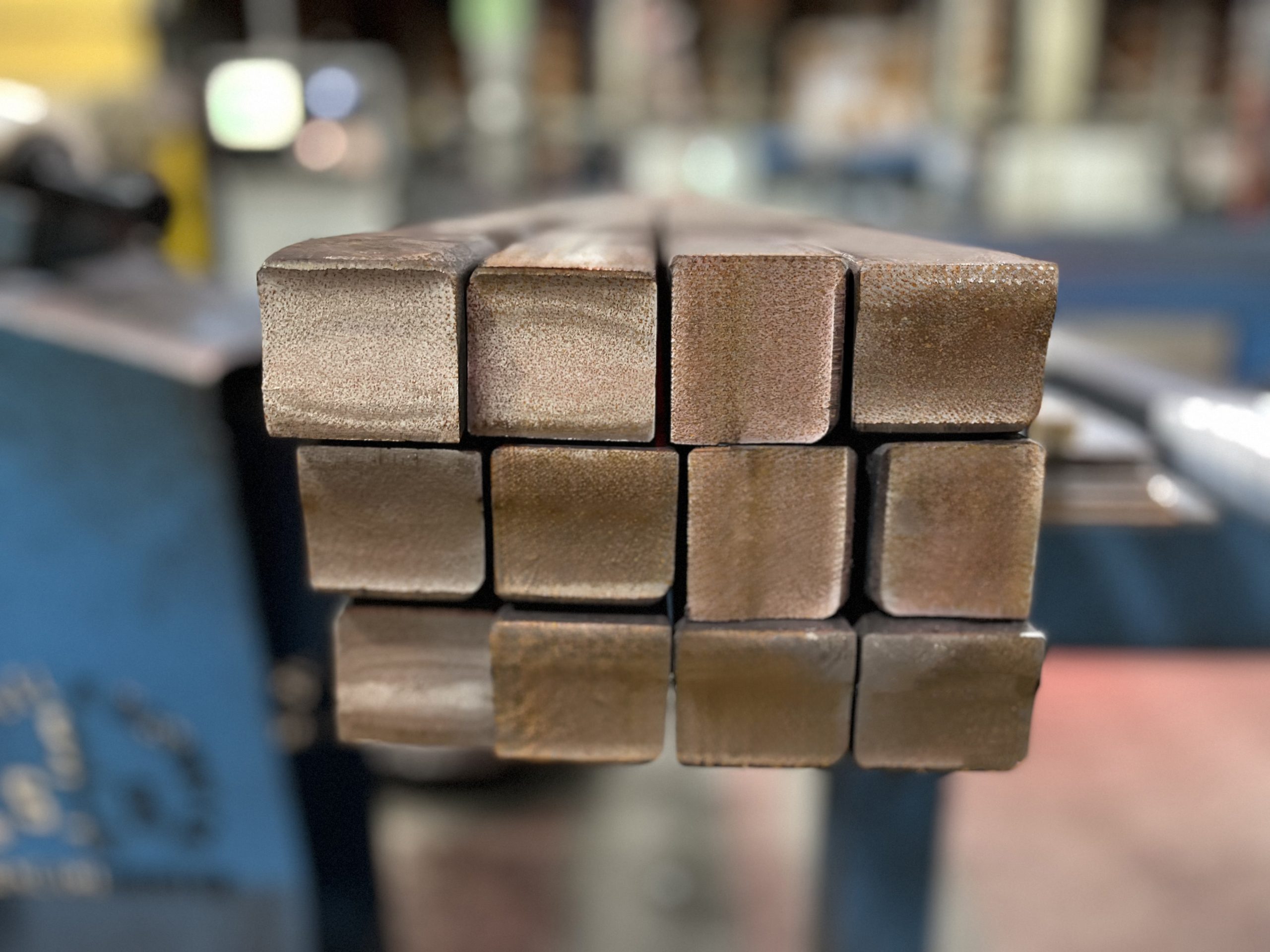 Up close view of 12 Steel Square Bars in an industrial background.