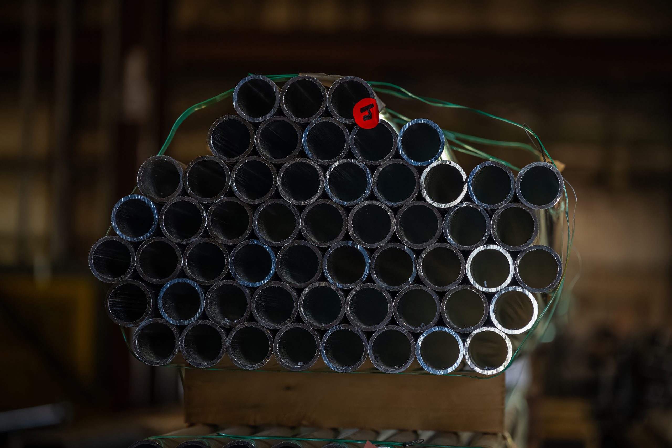 Close up of a stack of aluminum pipe on top of a wooden palette